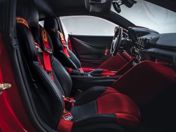 Binnenaanzicht van een Touring AERO 3-sportwagen met rode racestoelen, veiligheidsgordels en een modern dashboard.