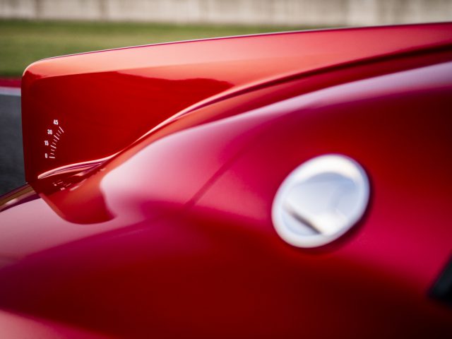 Close-up van de achterspoiler en tankdop van een rode sportwagen van de Touring AERO 3, met de nadruk op de glanzende afwerking en het strakke ontwerp.