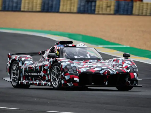 Een Toyota GR Super Sport hybride auto met een rood, wit en zwart camouflageontwerp snelt over een racecircuit.
