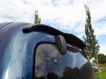 Achteraanzicht van een Toyota ProAce City Verso met een verhoogde spoiler met reflecterende kofferdeksel en bomen op de achtergrond.