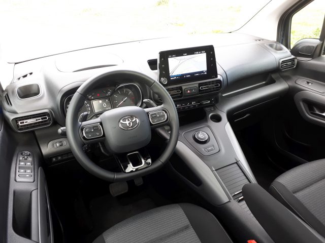 Binnenaanzicht van een Toyota ProAce City Verso met het stuur, het dashboard en het navigatiescherm.