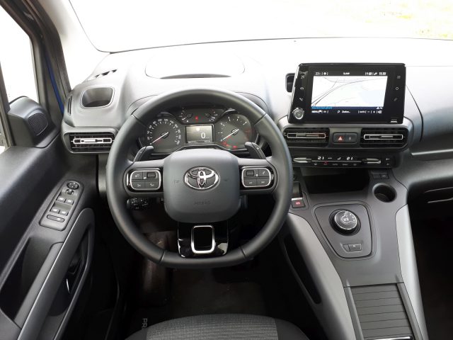 Binnenaanzicht van een Toyota ProAce City Verso, met stuurwiel, dashboard met meters, multimediadisplay en bedieningselementen op de middenconsole.