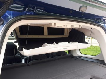 Open kofferbak van een blauwe Toyota ProAce City Verso met een gedetailleerd zicht op de bagageruimte met een toegankelijk opbergvak.