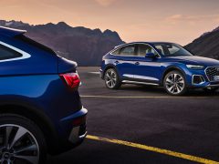 Twee Audi Q5 Sportback SUV's geparkeerd in tegengestelde richting op een bergweg bij zonsondergang, met een schilderachtige rotsachtige achtergrond.