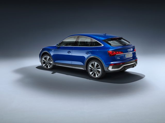 Blauwe Audi Q5 Sportback SUV weergegeven vanuit een driekwart perspectief aan de achterkant tegen een grijze achtergrond.