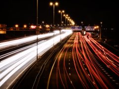 Foto met lange sluitertijd van een drukke snelweg 's nachts, met strepen witte en rode lichten van snelheidsvoertuigen.