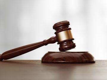 Houten rechtershamer op een bureau met een onscherpe achtergrond, symbool voor juridische autoriteit en gerechtelijke procedures waarmee een recordbedrag gemoeid is.