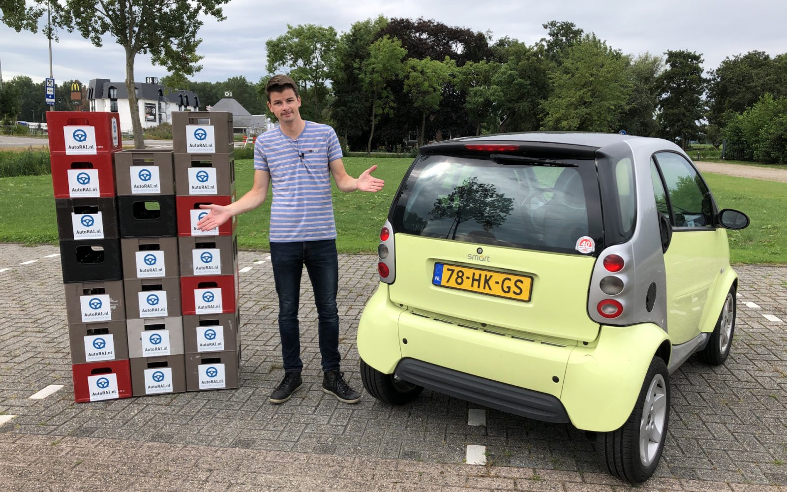 Een man staat naast een Nissan X-Trail met een stapel kartonnen dozen met daarop recyclingsymbolen.