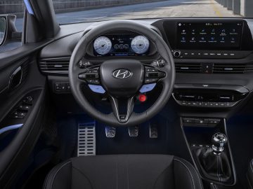 Binnenaanzicht van een Hyundai i20 N met het stuur, het dashboard met digitale displays, de middenconsole en de handgeschakelde versnellingsbak.