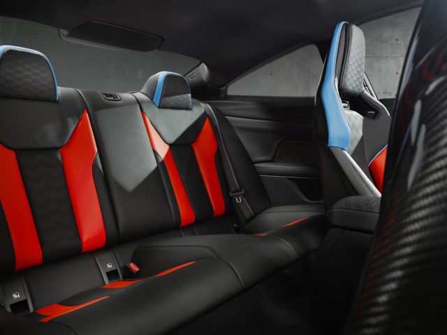 Binnenaanzicht van een BMW M4 Competition x KITH met kleurrijke en sportieve achterstoelen met rode, zwarte en blauwe details.