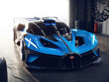 Een blauwe, hoogwaardige Bugatti Bolide met een opvallend aerodynamisch ontwerp, geparkeerd in een lichte, industriële garage.