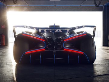 Achteraanzicht van een Bugatti Bolide-raceauto in een garage, met de nadruk op de brede vleugel en het futuristische ontwerp, verlicht door zonlicht.