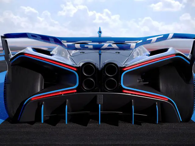 Achteraanzicht van een blauw-witte Bugatti Bolide-sportwagen met prominente quad-uitlaten op een racecircuit onder een heldere hemel.