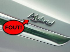 Close-up van een 'hybride auto'-embleem met een rode tekstballon met het woord 'fout!' wat een fout of vergissing aangeeft.