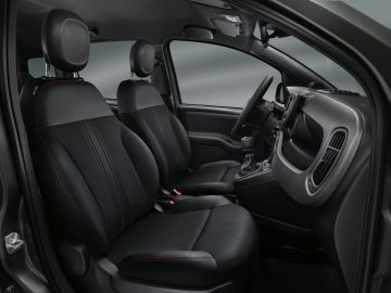Binnenaanzicht van een Fiat Panda Sport met de voor- en achterstoelen, het dashboard en het stuur, met zwarte bekleding en rode stiksels.