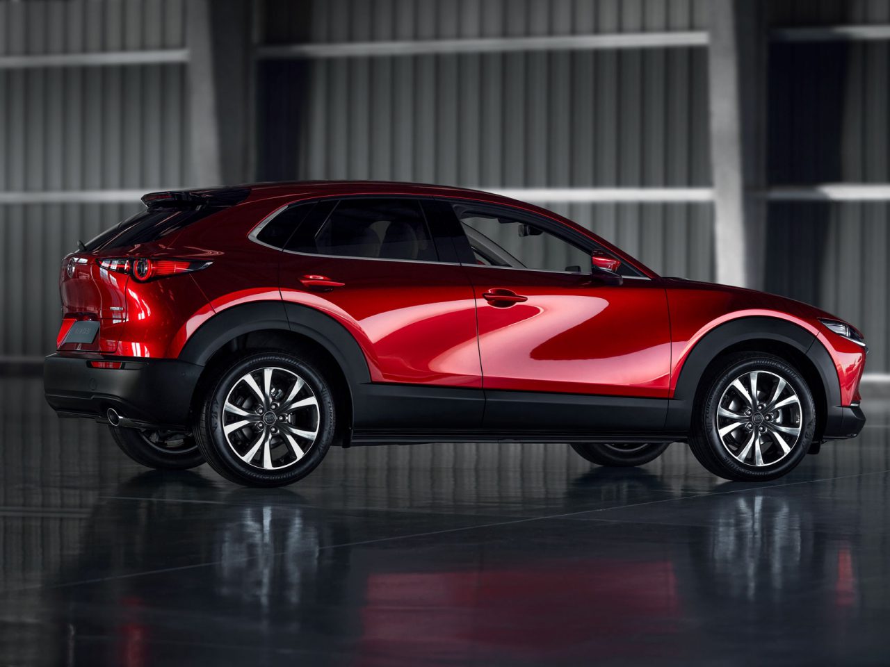 Rode Mazda-SUV geparkeerd in een slecht verlichte loods, waar de glanzende afwerking en het strakke, moderne ontwerp goed tot hun recht komen.