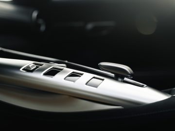 Close-up van het interieur van een Mercedes-AMG GT C Roadster, met de deur met bedieningsknoppen voor de ramen en zijspiegels, met hoogwaardige afwerking.