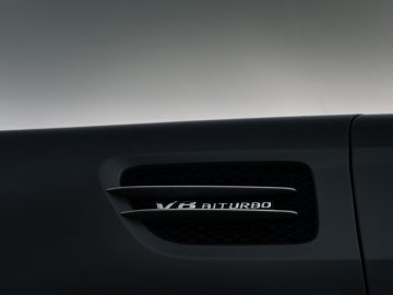 Close-up van het zijpaneel van een zwarte Mercedes-AMG GT C Roadster met een 'v8 biturbo'-badge, dat de capaciteiten van de motor benadrukt.