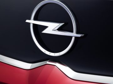 Close-up van het Opel Crossland-autologo op een rood voertuig, met een zilveren bliksemschicht in een cirkel.