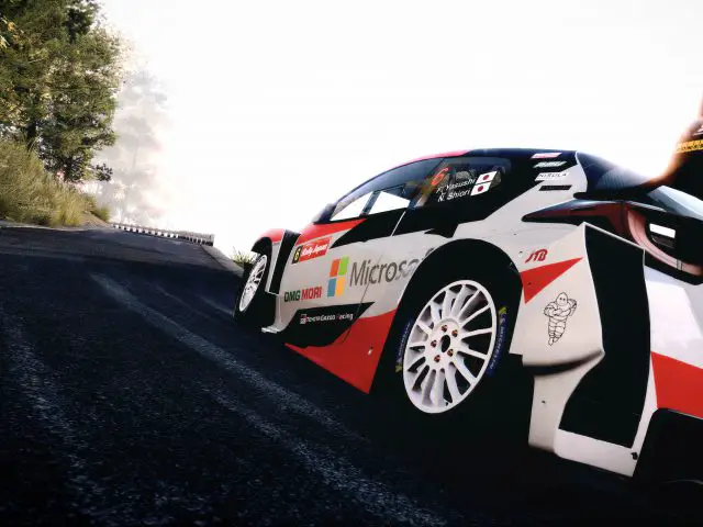 Rallyauto met sponsorstickers van Microsoft en Toyota GR Yaris Rally Concept die over een bochtige bergweg drijft, met bandenrook op de achtergrond.