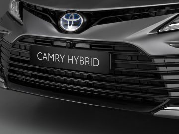 Close-up van de grille en het embleem van een Toyota Camry, waarbij het strakke ontwerp en het logo van de auto worden benadrukt.