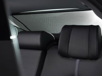 Binnenaanzicht van een Toyota Camry met zwartleren stoelen met gedetailleerde stiksels en duidelijk zicht op de hoofdsteunen en achterruit.