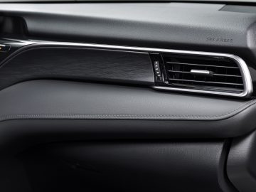 Close-up van het dashboard van een Toyota Camry met lederen afwerking en een gedetailleerde ventilatieopening met chroomaccent.