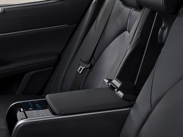 Binnenaanzicht van een Toyota Camry met zwartleren achterbank met een moderne middenarmsteun met een touchscreen-bedieningspaneel.