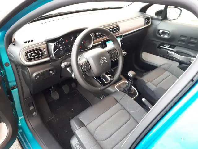 Binnenaanzicht van een Citroën C3-auto met het stuur, het dashboard en de voorstoelen vanaf de bestuurdersdeur.