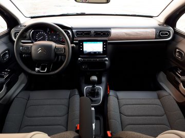 Binnenaanzicht van een Citroën C3 met het stuur met logo, dashboard, middenconsole met touchscreen en voorstoelen.