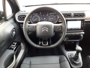 Binnenaanzicht van een Citroën C3-voertuig met het stuur, het dashboard en de middenconsole met een handgeschakelde versnellingsbak.