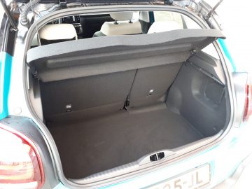 Open kofferbak van een blauwe Citroën C3 met een schoon, leeg interieur met de achterbank omhoog en een ingetrokken deksel erop.