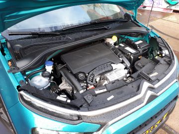 Motorruimte van een blauwe Citroën C3 met de motorkap open, met onderdelen als het motorblok en het koelvloeistofreservoir.