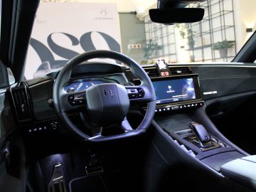 Binnenaanzicht van een moderne DS 9-auto met een stuur met embleem, digitaal dashboard en middenconsole.
