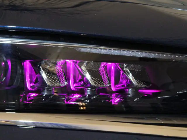 Close-up van de koplamp van een DS 9 met een modern ontwerp met ingewikkelde paarse LED-verlichting en reflecterende details.