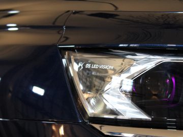 Close-up van de koplamp van een DS 9-auto met het opschrift 'DS LED Vision' op een strak zwart voertuig.