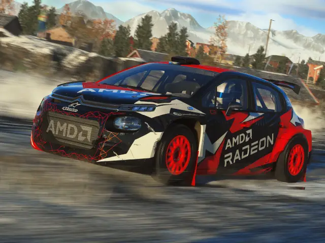 Een zwart-rode AMD Radeon-rallyauto die over een onverharde weg rijdt met besneeuwde bergen op de achtergrond, vastgelegd tijdens een DiRT 5-recensie.