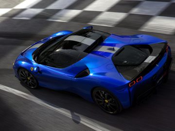 Een blauwe Ferrari SF90 Spider-sportwagen die over een zebrapad op een stedelijke weg rijdt.