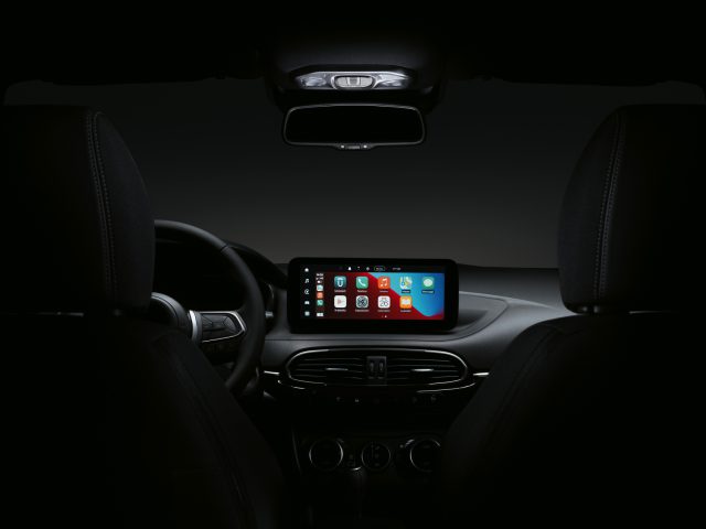 Interieur van een Fiat Tipo 's nachts met nadruk op het dashboard en het stuur, met een helder verlicht touchscreen met kleurrijke app-pictogrammen.