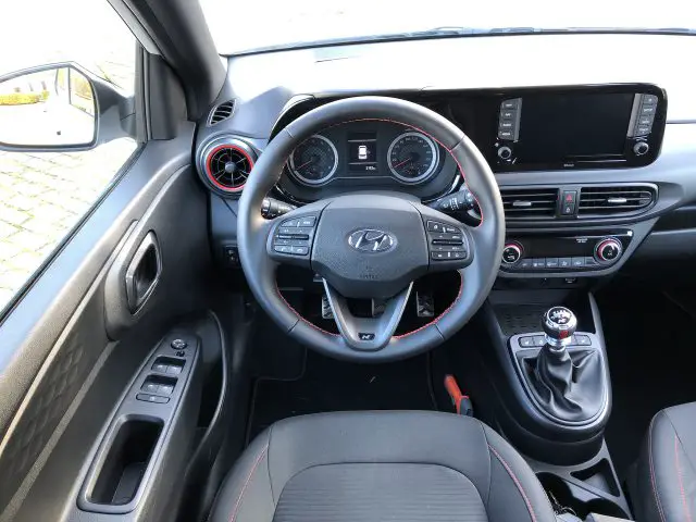 Binnenaanzicht van een Hyundai i10 N Line-auto met het stuur, het dashboard en de handgeschakelde versnellingsbak.