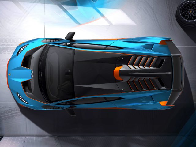 Bovenaanzicht van een strakke blauwe Lamborghini Huracán STO met oranje accenten en aerodynamisch design, geparkeerd in een moderne garage.