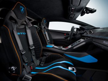 Binnenaanzicht van een Lamborghini Huracán STO-sportwagen, met twee blauw-zwarte stoelen met STO-logo, een strak dashboard en koolstofvezeldetails.
