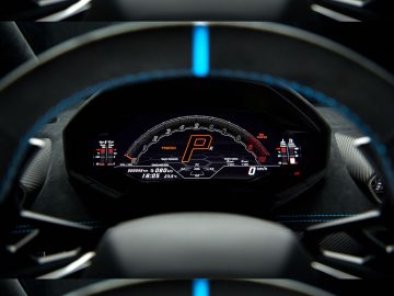 Drie digitale snelheidsmeters in een Lamborghini Huracán STO geven verschillende snelheids- en toerentalinstellingen weer, bekeken door een stuur.