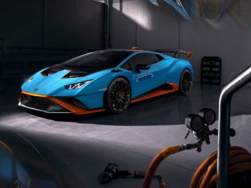 Een blauwe Lamborghini Huracán STO geparkeerd in een garage, met een scherp aerodynamisch ontwerp en levendige oranje accenten.