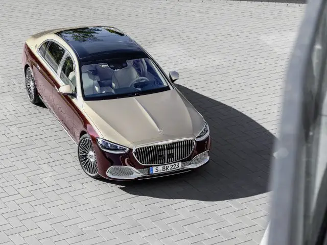 Luchtfoto van een luxe Mercedes-Maybach S-Klasse sedan met een prominente grille, geparkeerd op een buitenterrein met grijze straatstenen.