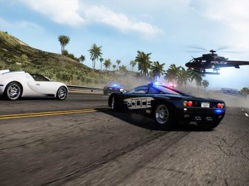 Politieauto met sirenes achtervolgt een witte sportwagen op een kustweg in Need for Speed Hot Pursuit Remastered, met een politiehelikopter erboven.