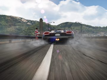 Een zilveren sportwagen snelt over een brug in een scène die doet denken aan Need for Speed Hot Pursuit Remastered, waardoor er bandenrook ontstaat met een wazig landschap op de achtergrond.