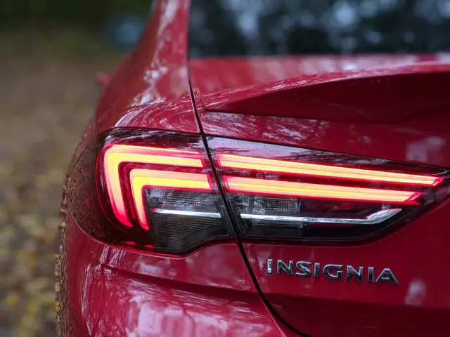 Close-up van het achterlicht van een rode Opel Insignia op een natte dag, met de details van het licht en de regendruppels.