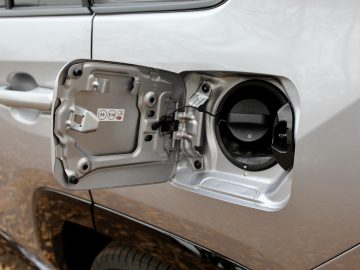 Open de tankdop van een zilveren Suzuki Across Plug-in Hybrid, waarbij de brandstofinlaat zichtbaar is terwijl de dop is verwijderd.