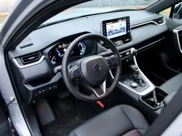 Binnenaanzicht van een Suzuki Across Plug-in Hybrid met de nadruk op het stuur, het dashboard en dubbele digitale displays.
